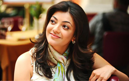 Kajal Aggarwal smiles warmly in this HD desktop wallpaper, showcasing her elegance and charm in a vibrant setting. A stunning background for fans of the actress.