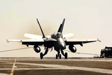 HD desktop wallpaper of a McDonnell Douglas F/A-18 Hornet military jet on a runway, captured head-on with a neutral, light background.