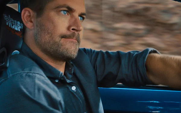 A high-definition desktop wallpaper featuring Paul Walker, capturing a moment of him driving with a focused expression against a blurred backdrop.