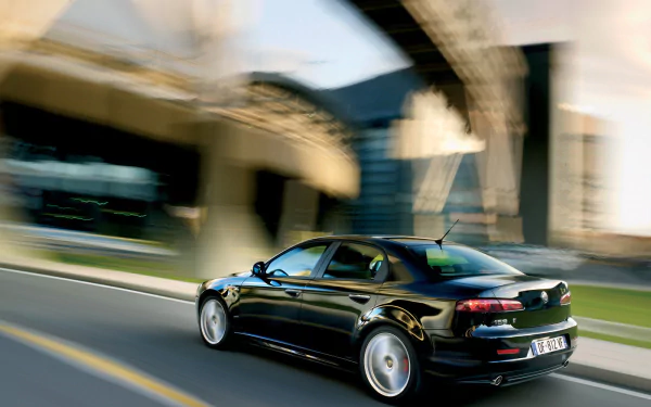 HD PC desktop wallpaper featuring a sleek black Alfa Romeo 159 driving on an urban road, highlighting the vehicle's dynamic design and motion.