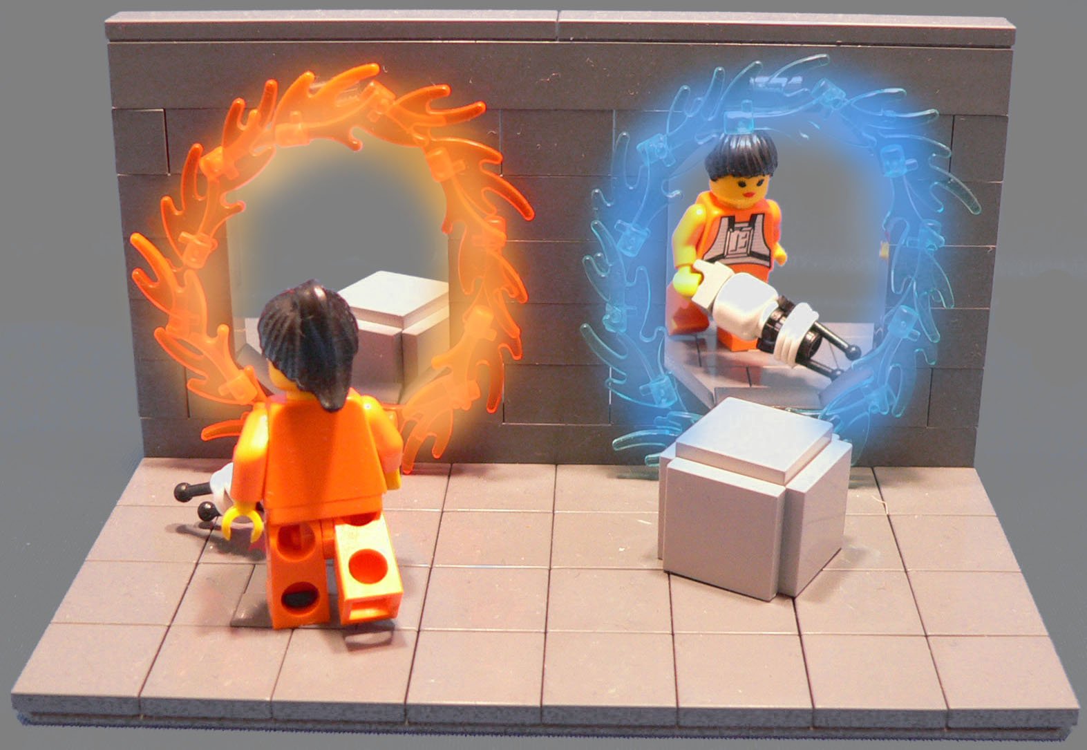 A vibrant HD PC wallpaper featuring LEGO figures from the video game Portal, interacting with orange and blue portals against a gray background.
