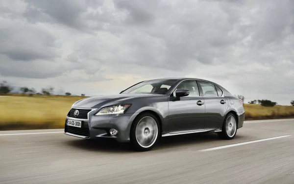HD desktop wallpaper featuring a sleek Lexus GS 300h driving on an open road under a cloudy sky, showcasing the vehicle's elegant design and dynamic presence.