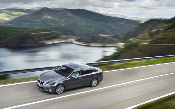 HD desktop wallpaper featuring a sleek Lexus GS 300h driving on a scenic mountain road by a lake, showcasing the elegance of the Lexus GS vehicle.