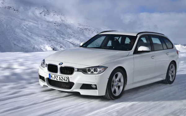 White 2013 BMW 320d touring through snow on a mountain road — HD PC desktop wallpaper background.