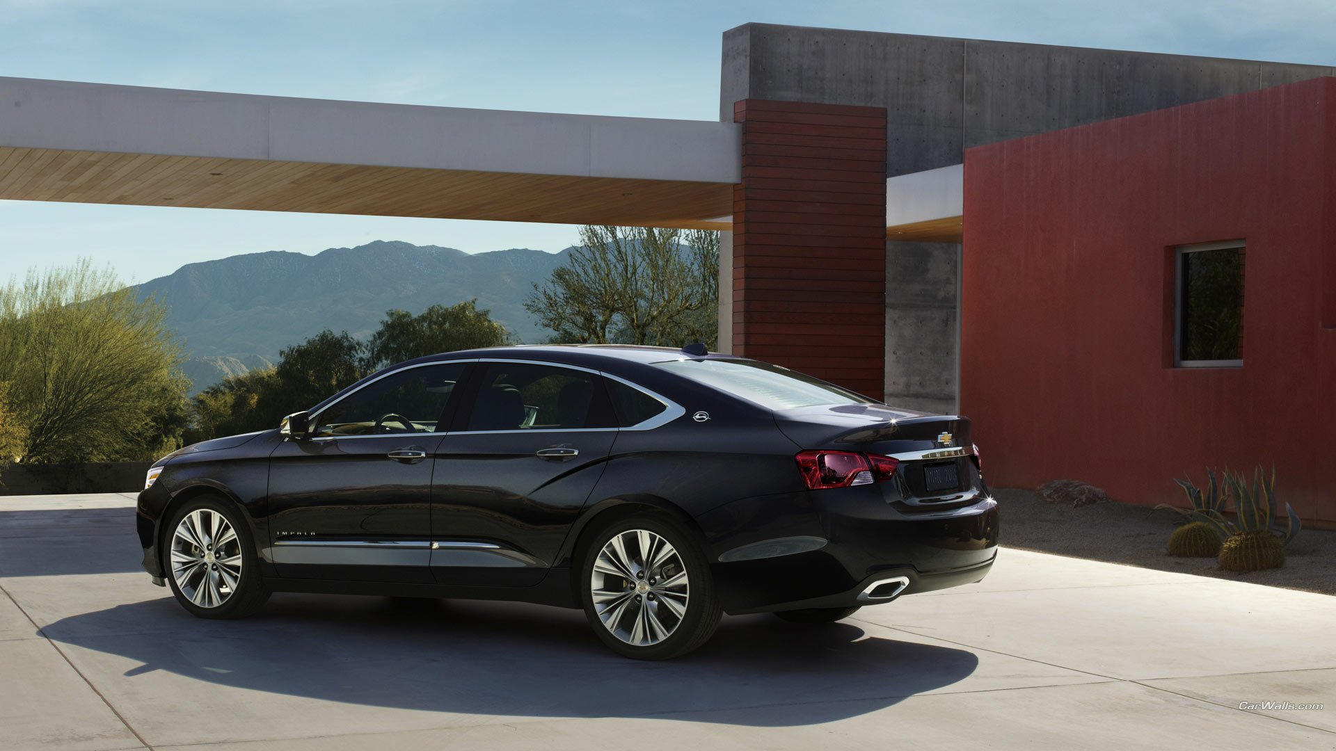 HD PC desktop wallpaper background showing a black Chevrolet Impala parked beside a modern home with desert plants and distant mountains.