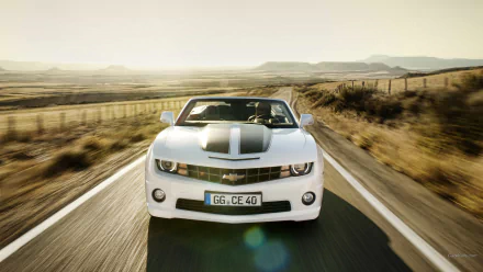 A white Chevrolet Camaro Convertible drives on an open road through a sunlit desert landscape, captured in a high-definition PC desktop wallpaper.