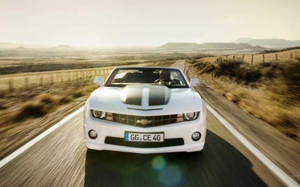A white Chevrolet Camaro Convertible drives on an open road through a sunlit desert landscape, captured in a high-definition PC desktop wallpaper.