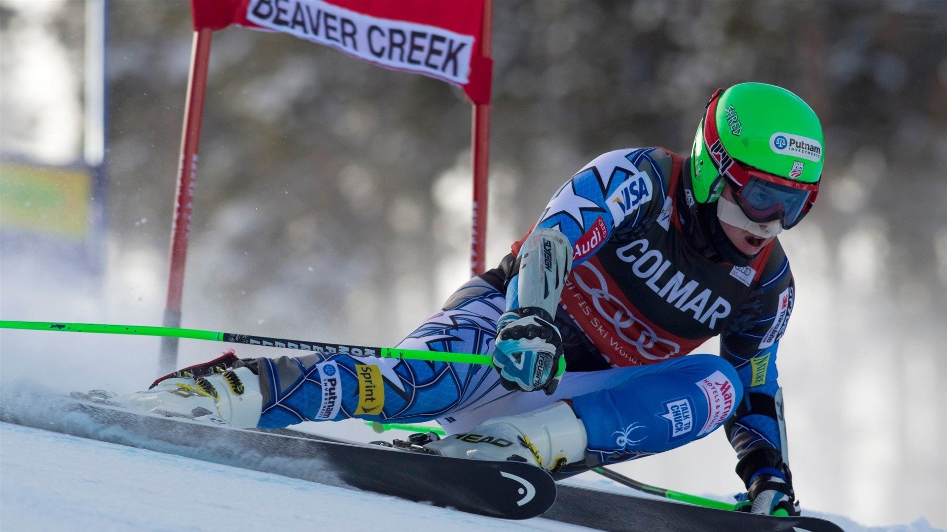 HD PC desktop wallpaper of slalom skiing — Sports action of a racer carving a low, high-speed turn at Beaver Creek, snow spraying.