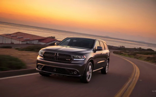 Dodge Durango vehicle cruising a coastal road at sunset, captured as an HD PC desktop wallpaper and background.