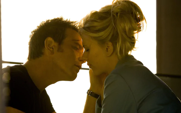 Film still from The Island: two actors in an intimate, backlit close-up with faces inches apart, warm tones — 2K Quad HD PC desktop wallpaper.