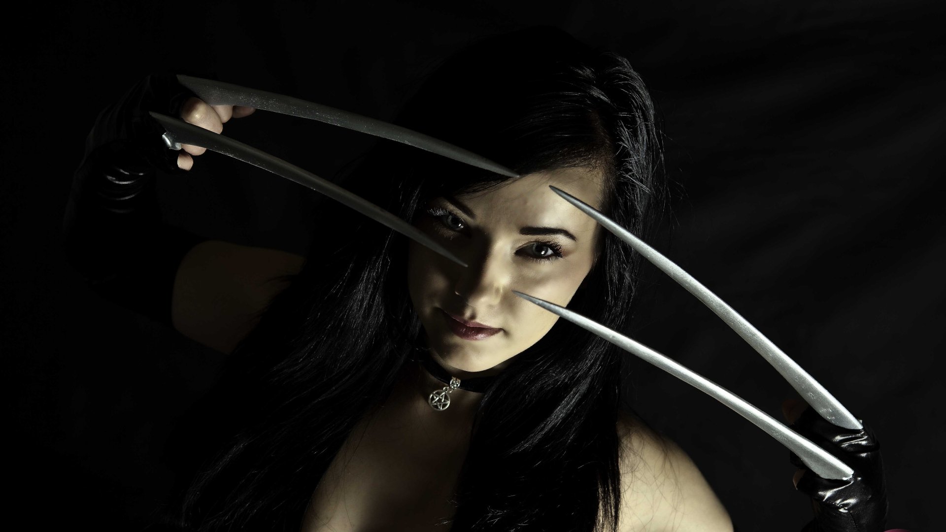 A woman in cosplay with dark hair poses dramatically, holding long metallic claws, captured in sharp detail for a 4K Ultra HD PC desktop wallpaper.