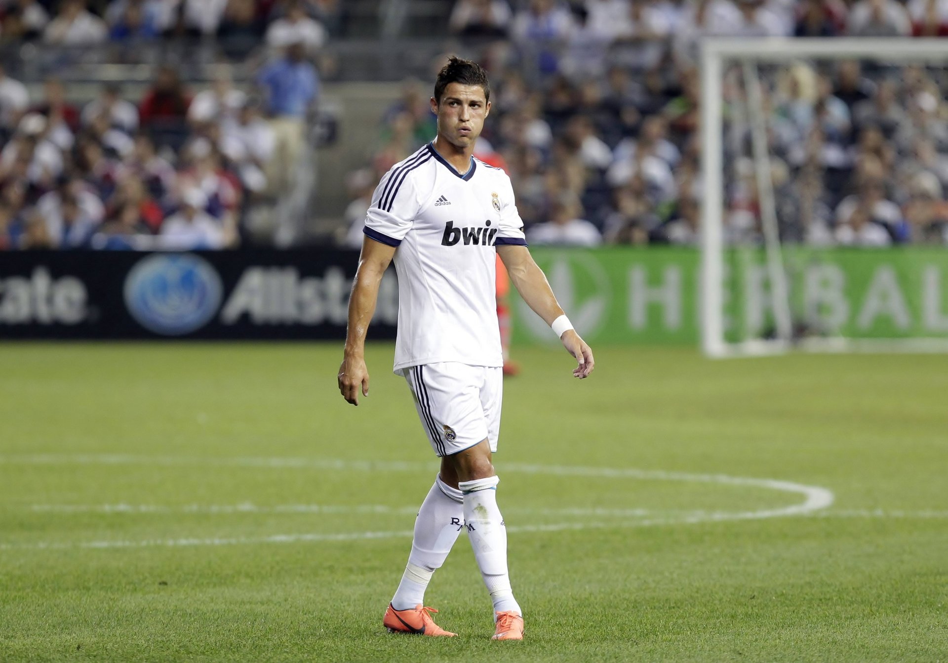 Cristiano Ronaldo walks on the field in a Real Madrid C.F. jersey during a match, captured in this HD desktop wallpaper, embodying the spirit of sports excellence.