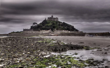 HD PC desktop wallpaper: Mont Saint-Michel's religious abbey atop a tidal island, moody clouds and rocky green-tinged foreground.