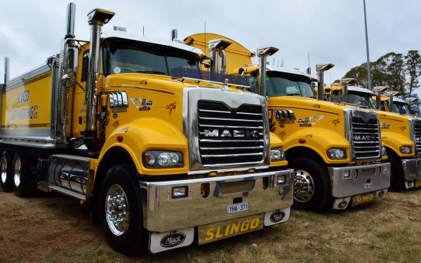 Bright yellow Mack Trucks are lined up outdoors, captured in sharp detail for a 4K Ultra HD PC desktop wallpaper featuring powerful vehicles.