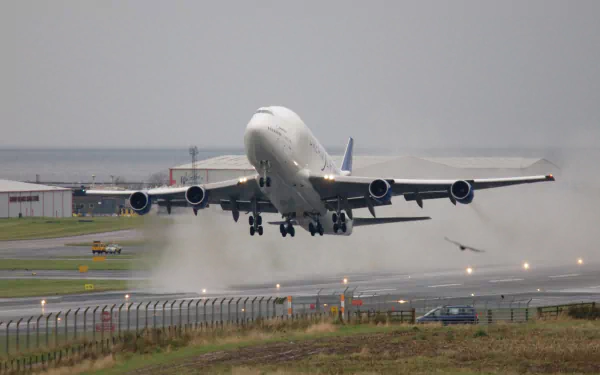 Boeing 747 Dreamlifter cargo plane lifting off a wet runway, spray behind wheels — Dreamlifter, Boeing, airplane, vehicle; 2K Quad HD PC desktop wallpaper/background.