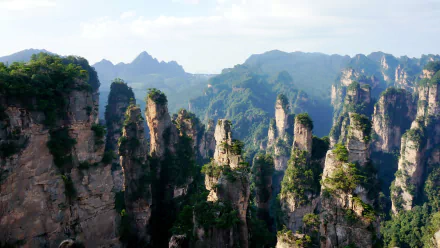 Scenic view of towering cliffs amidst lush greenery, capturing the majesty of nature. This HD wallpaper showcases stunning rock formations and a vibrant landscape.
