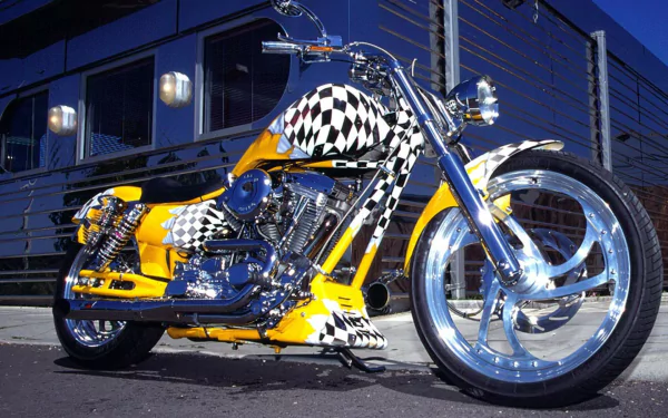 A custom Harley-Davidson motorcycle with a yellow body and black-and-white checkered pattern, parked in front of a modern building. HD desktop wallpaper and background.