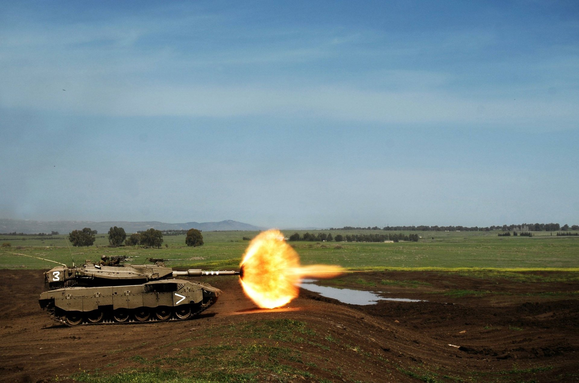 HD desktop wallpaper featuring a Merkava tank of the army firing on an open field under a clear sky.