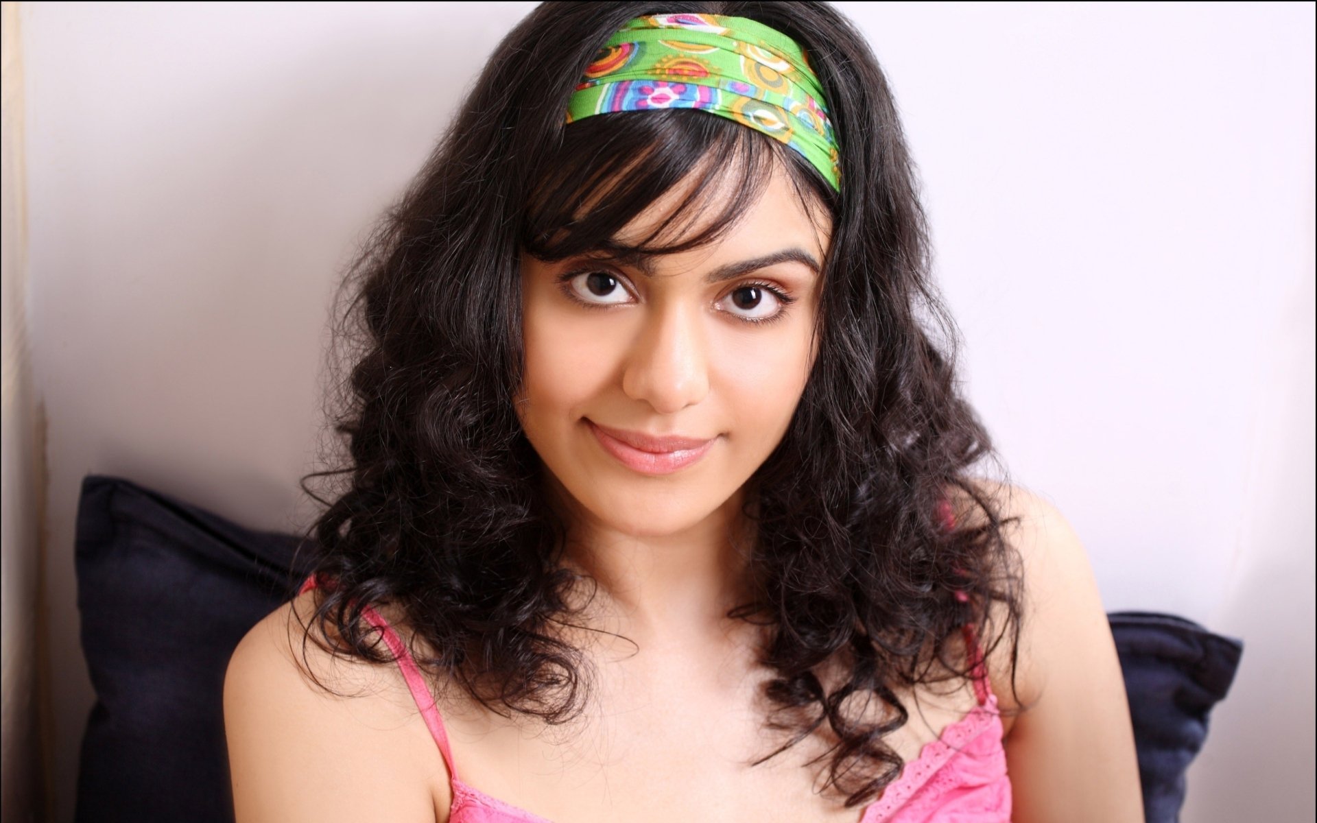 Adah Sharma poses with curly hair and a colorful headband, smiling softly. This high-definition image serves as a striking PC desktop wallpaper and background.