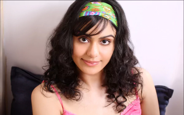 Adah Sharma poses with curly hair and a colorful headband, smiling softly. This high-definition image serves as a striking PC desktop wallpaper and background.