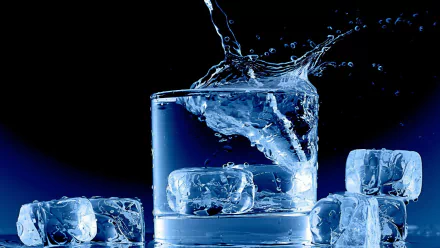 A stunning HD photograph of ice cubes splashing into a glass of water, set against a dark background, creates a refreshing and dynamic visual for desktop wallpaper.
