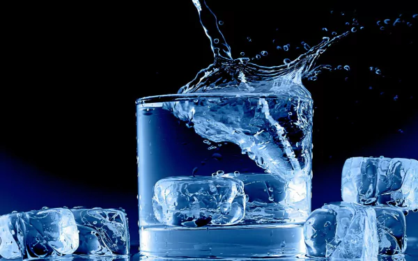 A stunning HD photograph of ice cubes splashing into a glass of water, set against a dark background, creates a refreshing and dynamic visual for desktop wallpaper.