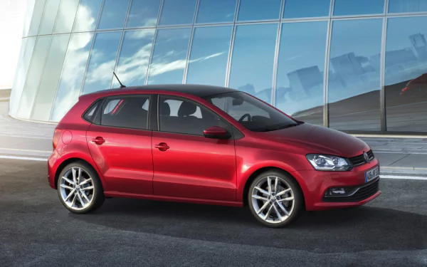 Red Volkswagen Polo vehicle in side profile against a reflective glass facade — HD PC desktop wallpaper and background.