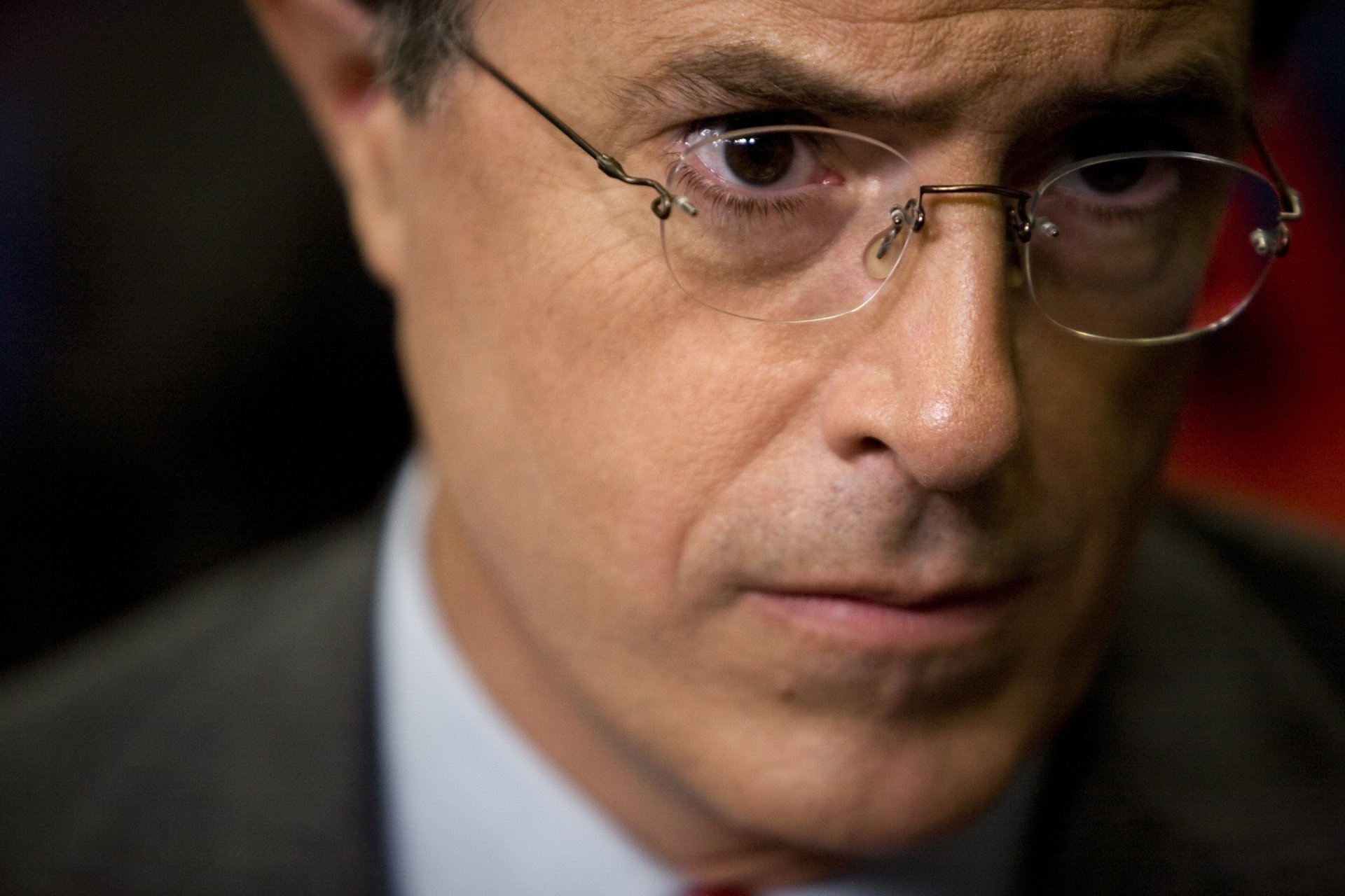 HD desktop wallpaper featuring a close-up of a man wearing glasses, with a serious expression.