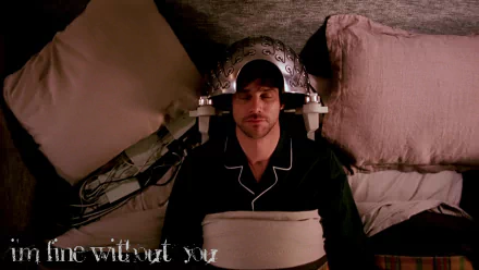 HD wallpaper from Eternal Sunshine of the Spotless Mind featuring Jim Carrey with a memory-erasing headpiece, lying on a bed.