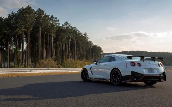 White Nissan GT-R Nismo vehicle on an open road by pine trees under a clear sky — HD PC desktop wallpaper/background