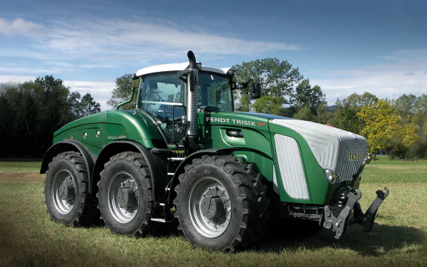 A Fendt Trisix Vario tractor stands on lush grass, showcasing its sleek design and robust tires, set against a vibrant natural background in this HD desktop wallpaper.