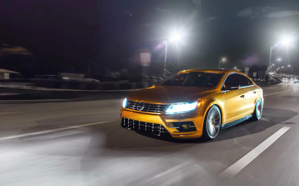 A sleek orange Volkswagen CC speeding on a nighttime highway, captured in stunning 4K Ultra HD as a dynamic PC desktop wallpaper and background.