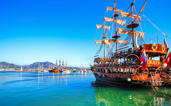 HD desktop wallpaper featuring a vibrant scene with the Dragon ship and other tall ships in a crystal-clear blue harbor under a bright sky.