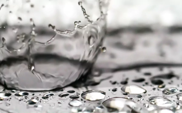 Close-up 4K Ultra HD photography of a water drop splash creating ripples and droplets on a reflective surface, capturing intricate water details.
