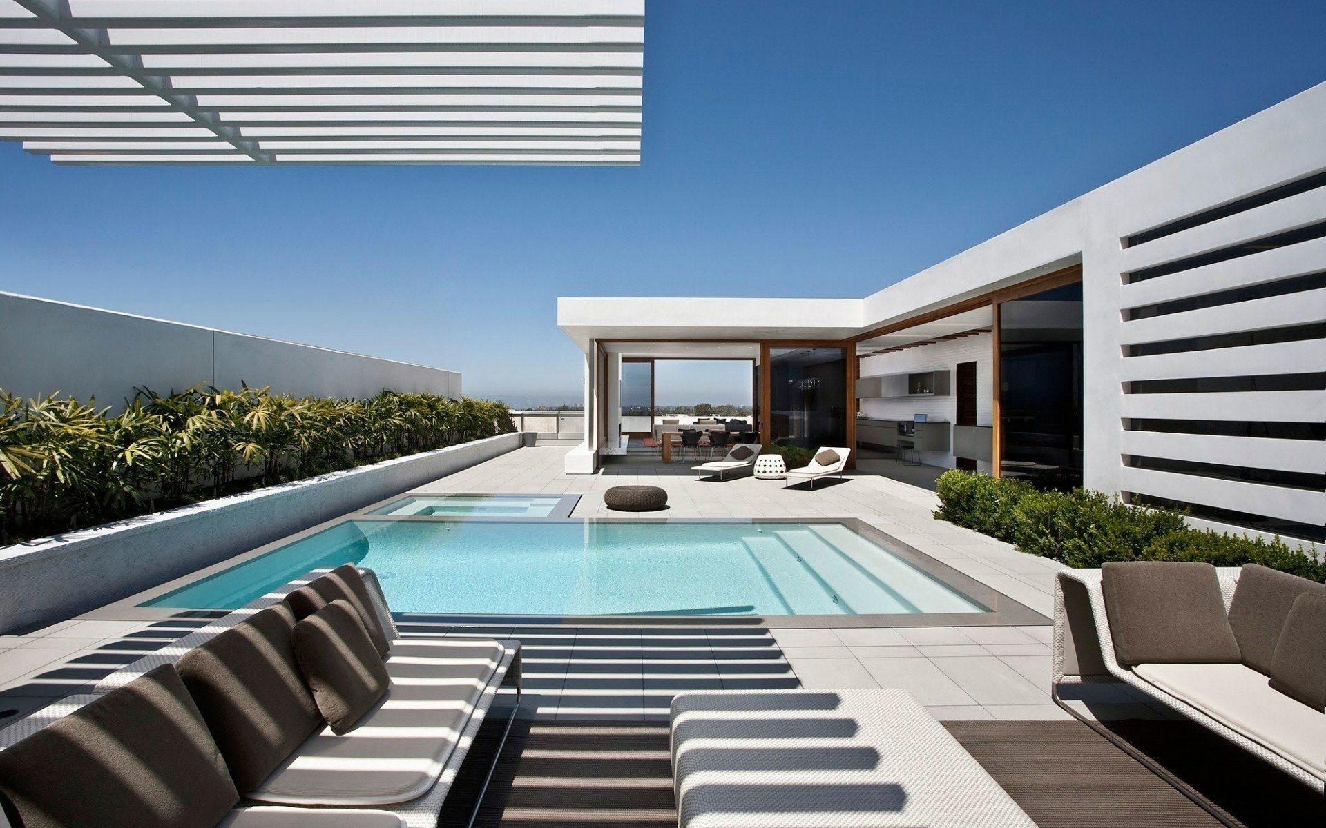 HD desktop wallpaper showing a modern man-made pool area with sleek outdoor seating and a minimalist architectural design under a clear blue sky.