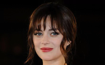 HD desktop wallpaper featuring a close-up portrait of French actress and celebrity Marion Cotillard with soft lighting and a dark background.