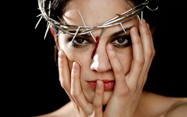 A striking HD wallpaper featuring Italian actress Asia Argento, her face framed by a thorn crown, conveying a powerful and intense emotional expression.