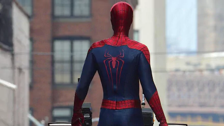 HD desktop wallpaper featuring Spider-Man from The Amazing Spider-Man 2, showing the superhero from behind in his iconic red and blue suit. The background depicts a cityscape with buildings.