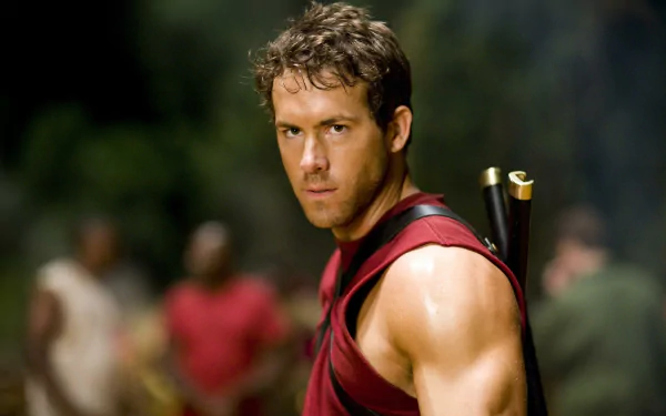 HD desktop wallpaper featuring Ryan Reynolds in a red sleeveless shirt carrying arrows, set against a natural, blurred background.