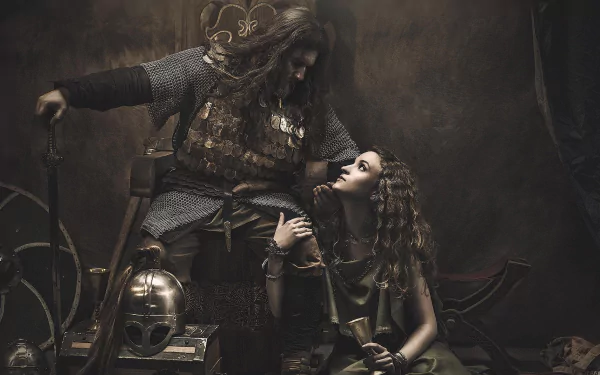 HD fantasy warrior desktop wallpaper featuring a battle-worn armored warrior gripping a sword, gazing intensely at a woman with flowing hair in a dark, dramatic setting.