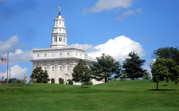 HD PC desktop wallpaper featuring the white Nauvoo Temple under a bright blue sky with green grass and trees in the foreground, highlighting its religious significance.
