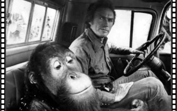 Black-and-white HD PC desktop wallpaper: film still from Every Which Way But Loose showing a man behind the wheel of a pickup with an orangutan in the passenger seat.