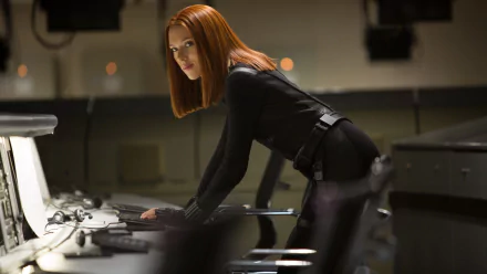 Scarlett Johansson as Black Widow in an intense scene from Captain America: The Winter Soldier, featuring her in a sleek black suit, focused at a control station. HD wallpaper background.