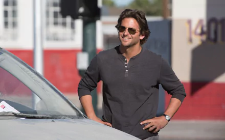 HD PC desktop wallpaper featuring American actor and celebrity Bradley Cooper smiling outdoors in casual attire and sunglasses.