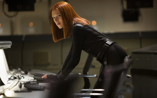 Scarlett Johansson as Black Widow in an intense scene from Captain America: The Winter Soldier, featuring her in a sleek black suit, focused at a control station. HD wallpaper background.