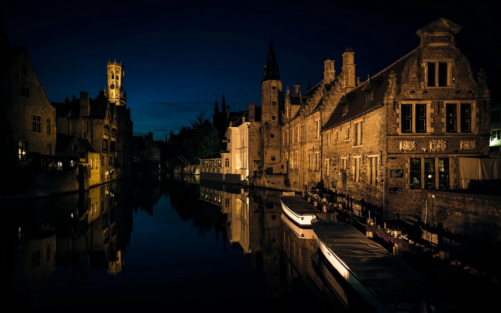 Nighttime view of historic Bruges buildings and a canal, showcasing man-made architecture reflected in calm water, captured in HD for a desktop wallpaper.