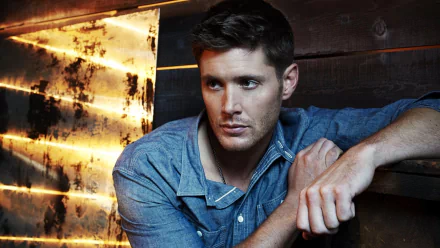 A high-definition wallpaper featuring Jensen Ackles as Dean Winchester from the TV show Supernatural, showcasing a contemplative moment against an artistic backdrop.