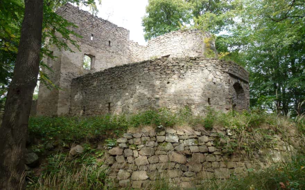 Man-made Bolczów Castle stone ruins among trees, weathered fortress walls and mossy terraces, shown as a 2K Quad HD PC desktop wallpaper/background.