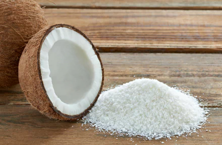 A close-up of a halved coconut next to a pile of shredded coconut on a wooden surface, creating a vivid food-themed HD desktop wallpaper.