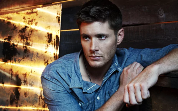 A high-definition wallpaper featuring Jensen Ackles as Dean Winchester from the TV show Supernatural, showcasing a contemplative moment against an artistic backdrop.